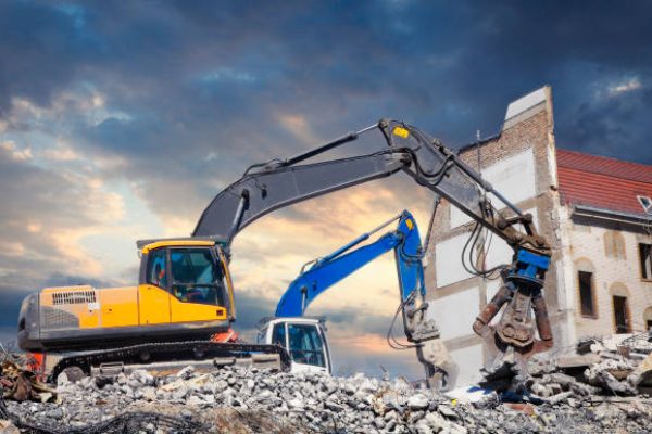 Bulldozers demolishing old house at construction site